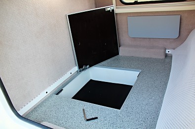 Pod spací matrací je úložný prostor v podlaze přívěsu. Minikaravan Tomplan od Tanatechu.